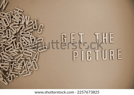 GET THE PICTURE in wooden English words language capital letters spilling from a pile of letters in sepia