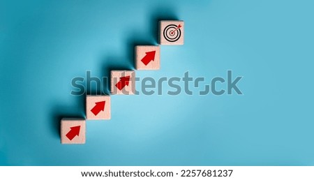 Virtual target board and increasing arrow icon on wooden cube. Business achievement goal and objective target concept. Blue background with copy space. Royalty-Free Stock Photo #2257681237
