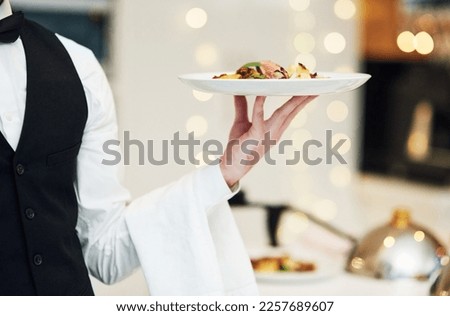 Fine dining, food and waiter serving at a restaurant for a luxury valentines day or anniversary meal. Formal, hospitality service and server with a plate or dish for a fancy special dinner date. Royalty-Free Stock Photo #2257689607