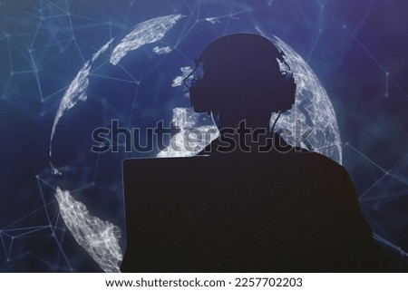 Silhouette of a military man in headphones at a laptop against the background of a digital globe of the earth, contour lighting. Concept: collection of confidential information, surveillance. Royalty-Free Stock Photo #2257702203