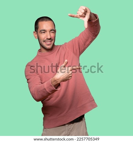 Amazed young man making a gesture of taking a photo with the hands