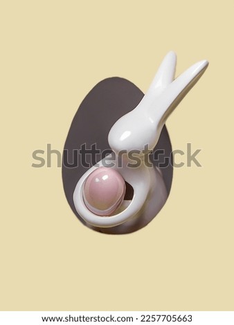 The ceramic Easter Bunny holding the pink Easter Egg is peeking out of the paper hole.