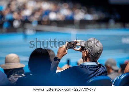 Fan taking a photo with a camera phone at a sporting event in Australia 