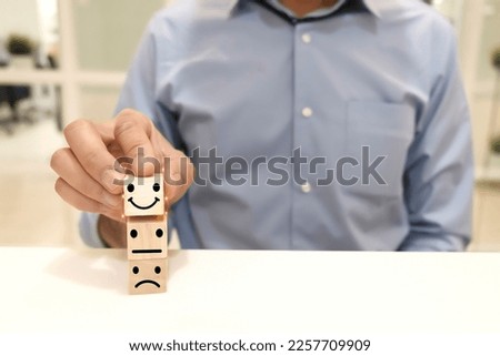 The customer's hand chooses a smiley face icon on the wood cube. Customer service evaluation and satisfaction survey service rating concepts.