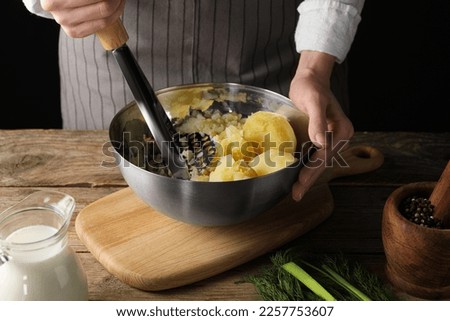 Woman making mashed potato at wooden table, closeup Royalty-Free Stock Photo #2257753607