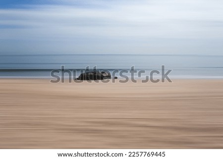 An isolated rock on a beach with a path blur abstract edit.