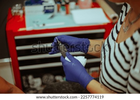 Close up of tattoo artist getting ready with her needle while sitting at the studio