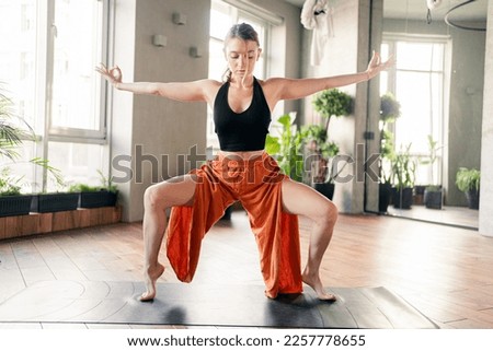 Exercise asana pose in the sports direction of yoga, a flexible woman stands on her toes using a mat.