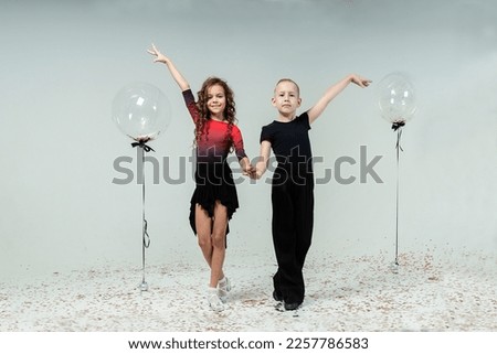 a curly-haired girl and a boy engaged in ballroom dancing pose showing elements of dancing