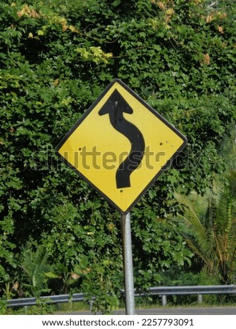 Winding road sign. Drivers encountering a winding road sign must be prepared to slow down as the sign designates a section of curved road ahead. Royalty-Free Stock Photo #2257793091