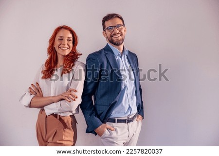 Business partners posing in front of gray background, looking at camera and smiling. Royalty-Free Stock Photo #2257820037