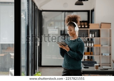 American woman standing with headphones in her room, she is resting and listening to music playing social chatting with friends. concept of relaxation.