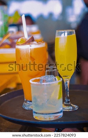 close up of a transparent glass filled with a chilled orange drink and lemon flavour  in soft focus to the background