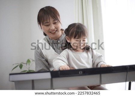 Parents and children practicing playing the piano Royalty-Free Stock Photo #2257832465