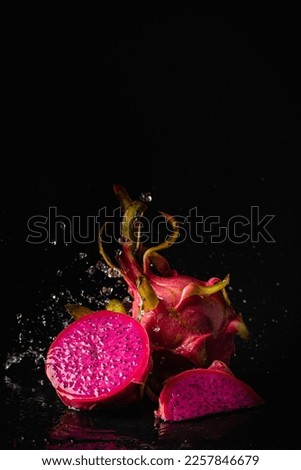 Ripe fresh red Dragon fruit or pitaya with slice part and water splashing on black background