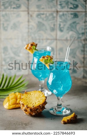 Boozy Blue Hawaii Cocktail with Rum and Pineapple on gray background