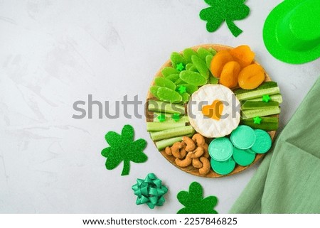 St Patrick's day charcuterie board with cheese, dried fruits and  shamrock on bright background. Top view, flat lay