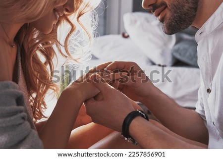 Close-up of young man putting engagement ring on finger of his happy girlfriend Royalty-Free Stock Photo #2257856901