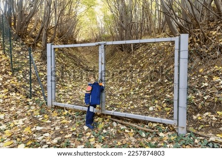 Illegal gate on Fruska Gora mountain in Serbia. The boy is standing by the gate in forest