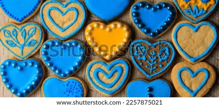 Top view of many heart shaped cookies decorated by yellow and blue icing and sprinkles. Valentine’s Day card. Ukrainian national colors