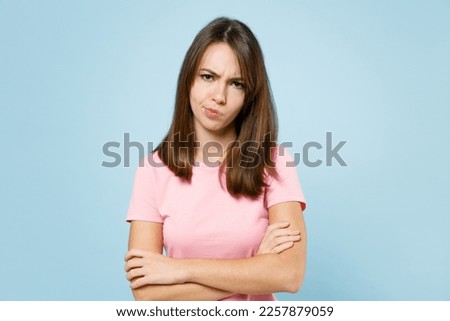 Young sad disappointed displeased caucasian woman 20s wear pink t-shirt look camera hold hands crossed folded isolated on pastel plain light blue background studio portrait. People lifestyle concept Royalty-Free Stock Photo #2257879059