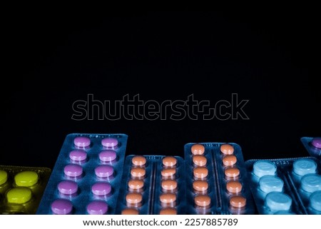 Red and orange pills in blister packs over black background
