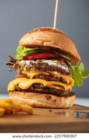 Loaded cheeseburgers three triple, stacked patties stacked high with layers of cheese, lettuce, and tomato. Tall cheeseburger