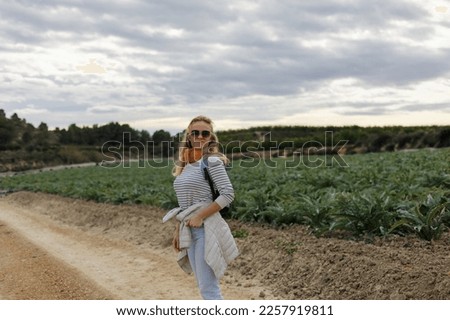 Portrait of a tourist woman looks at artichoke agricultural fields