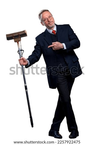 Senior man in suit holding a boom. Manager man pointing at mop in the studio on a white background.