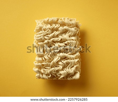 uncooked noodles on yellow background, top view