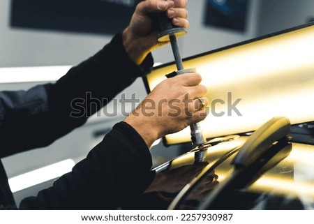 Unrecognizable male mechanic removing dents from car body using bright lamp and specialistic equipment. Mechanic's and car repair studio. High quality photo Royalty-Free Stock Photo #2257930987