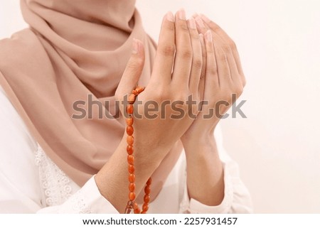 Close up photo of Young asian muslim woman's hand praying and holding prayer beads. Isolated on white