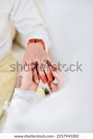 Hand of the bride wears a wedding ring to the groom.