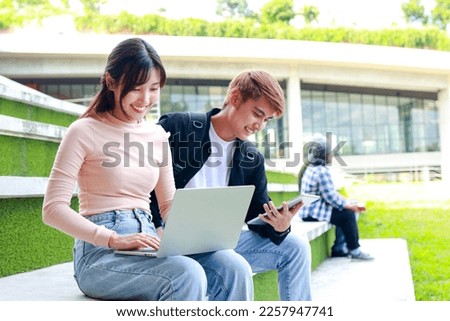Asian university students use laptops to study projects. Sit on the concrete floor outdoors on campus. Education concept. copy space