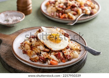 Corned beef hash with potatoes, cabbage and carrot on a plate topped with a fried egg Royalty-Free Stock Photo #2257950339