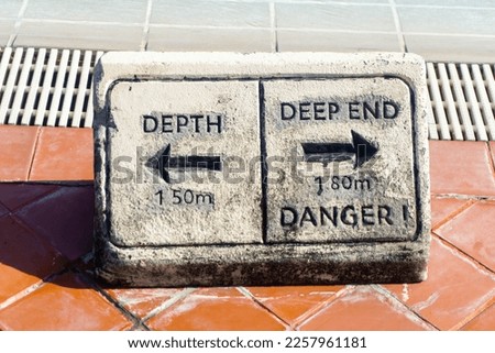 Warning sign by the pool. labeled "Depth" and "Deep End"