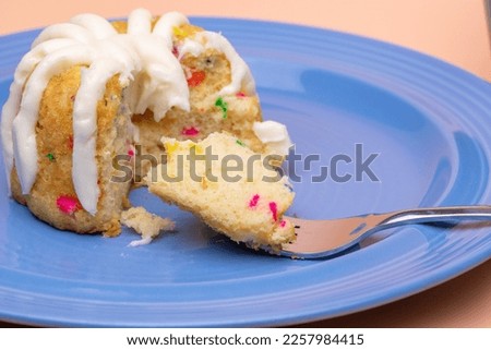 Confetti Bunt Cake on blue plate with cream cheese frosting