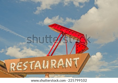 Generic restaurant sign with neon tubes on Route 66.  The red arrow has bulbs in it.