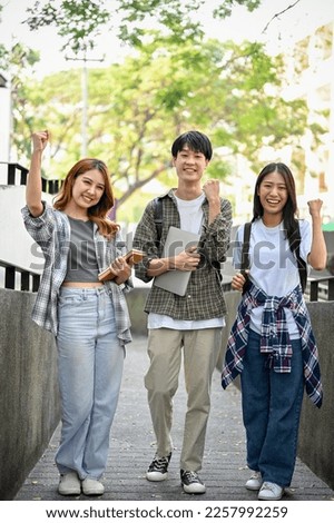 Group of cheerful young Asian college students showing fists, clenched fists, celebrating triumph, passing the exam, and enjoying university life.  Royalty-Free Stock Photo #2257992259