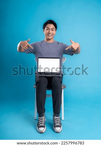 Full body youngAsian  using laptop and posing on blue background
