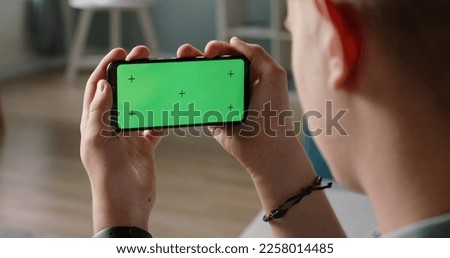 Man using a smart phone with mock up green screen, talking while having an online conference - online education, communications concept close up 