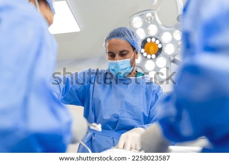 Group of medical team urgently doing surgical operation and helping patient in theater at hospital. Medical team performing surgical operation in a bright modern operating room