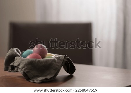 Easter eggs in a bowl with napkin on walnut wood table with copy space