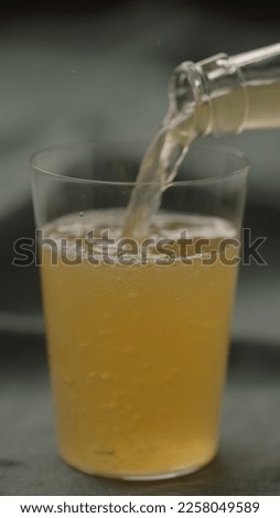 pour yellow drink in tumbler glas on linen cloth