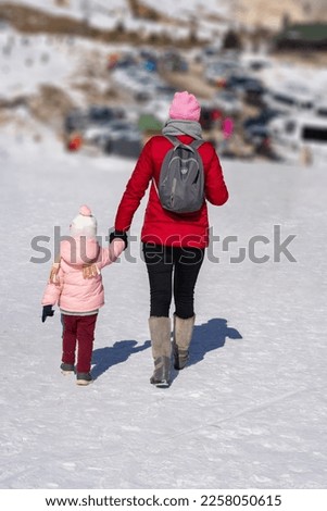 Woman walking in the snow with her child in Saklıkent, Antalya                              