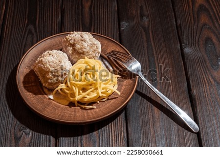 Spaghetti with meatballs with cream sauce on a clay plate. Background picture.
