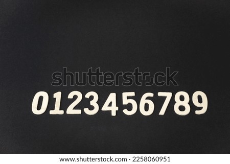 wooden numbers of 0 to 9 on black paper background