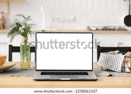 Modern computer, laptop with blank screen on table with blur modern kitchen backgrounds, kitchen worktop with blank laptop screen