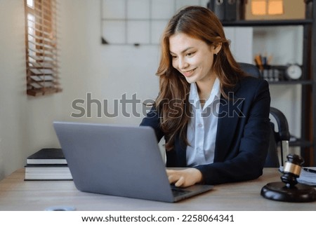 Justice and law concept. Female in a courtroom with the gavel working with digital tablet computer docking keyboard on wood table.