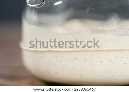 Feeding sourdough starter in a glass mason jar for baking artisan bread.
